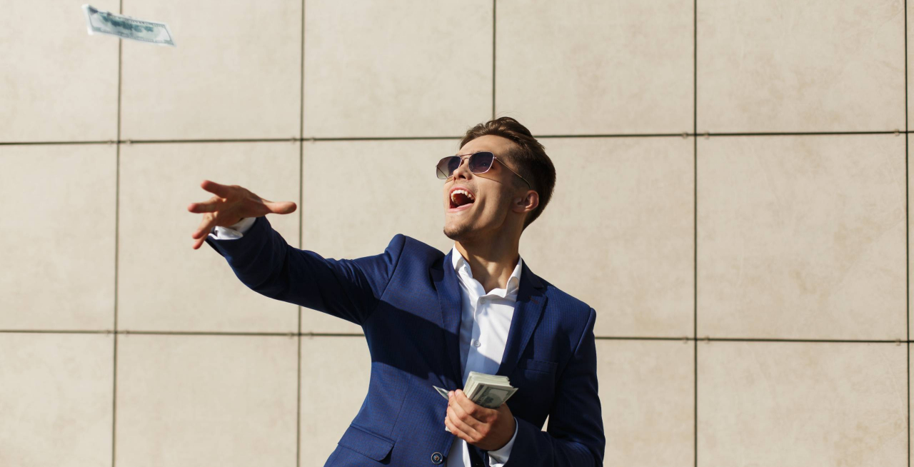 Young businessman throughs around dollars and dances on the street